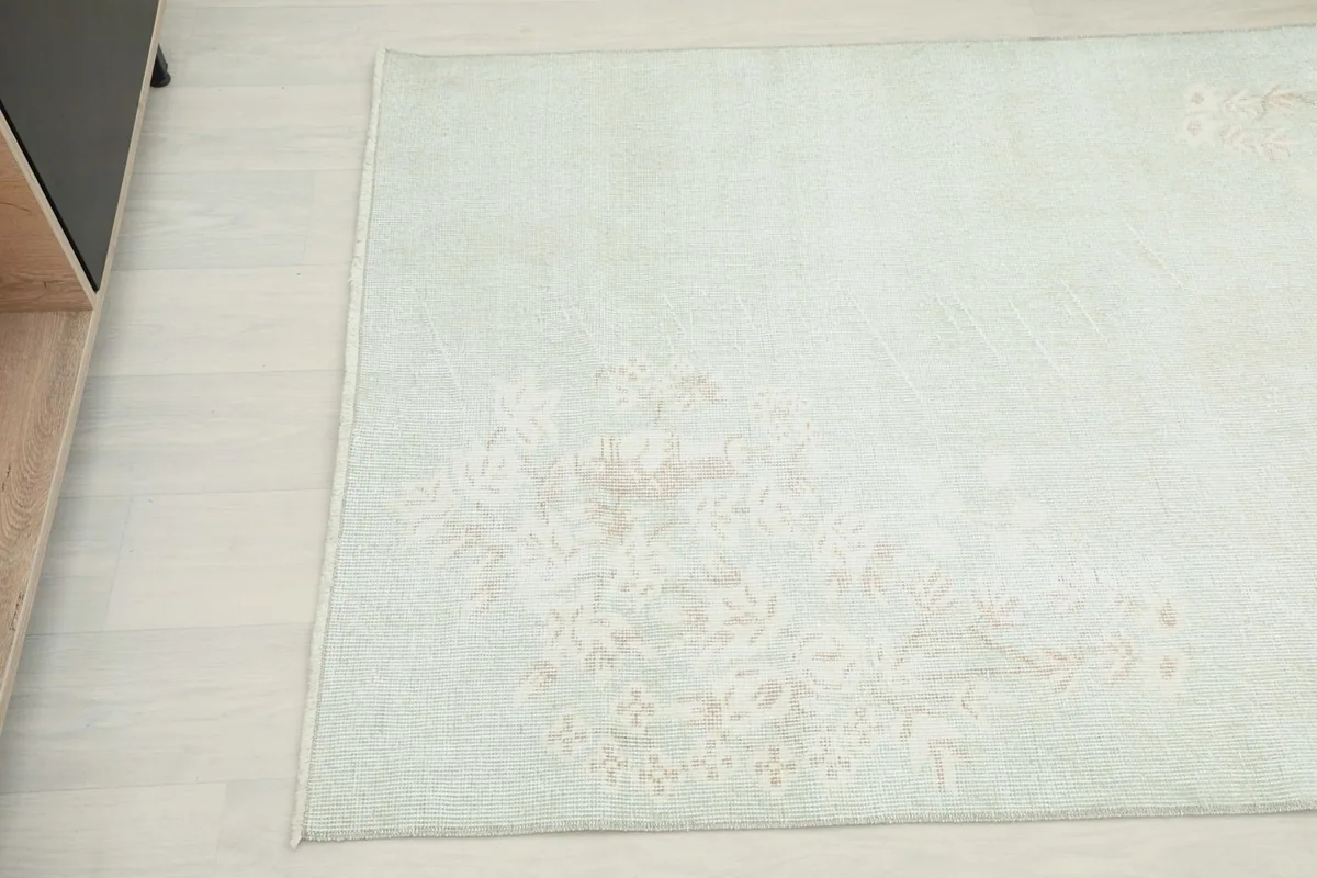 Corner view of the rug, showing subtle floral patterns and distressed areas