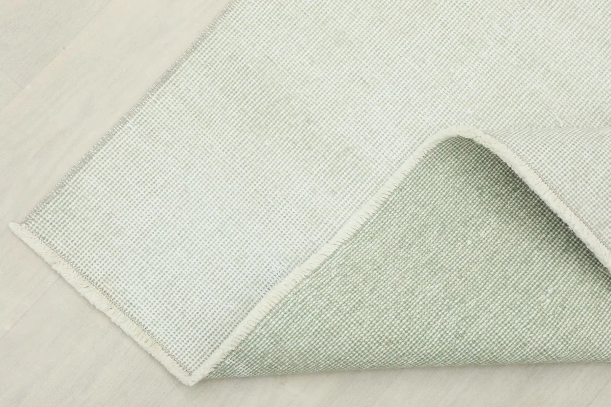 Corner of the rug folded back, showing the wool pile and cotton foundation