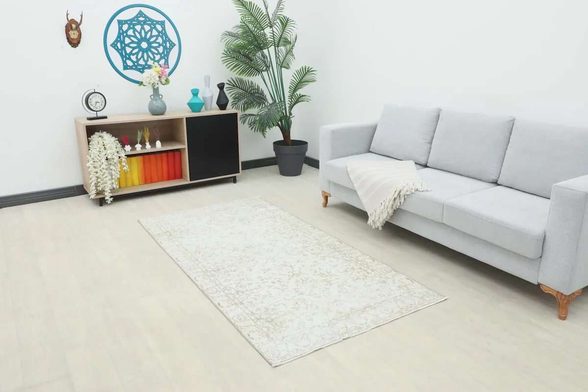Beige vintage rug placed in a modern living room setting with a light gray sofa