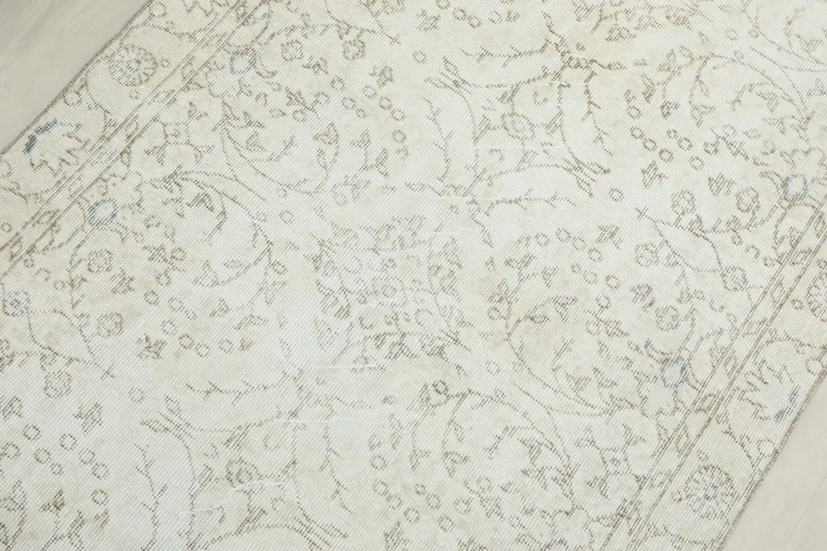 Detailed view of the rug's surface, showing the faded gray and cream floral patterns