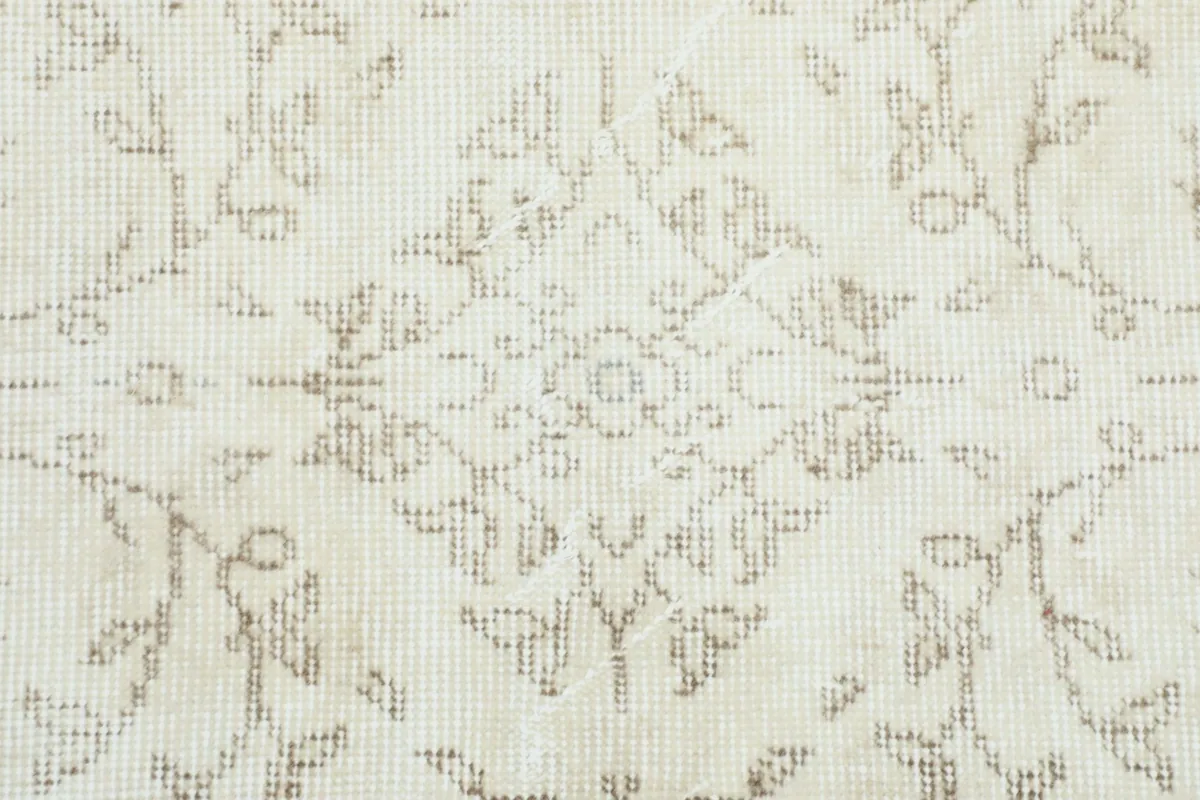 Close-up of the central medallion-like motif and surrounding patterns on the beige rug