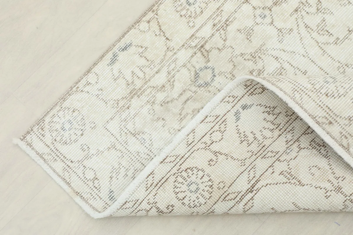 The corner of the rug folded back, revealing the cotton foundation and fine knotting
