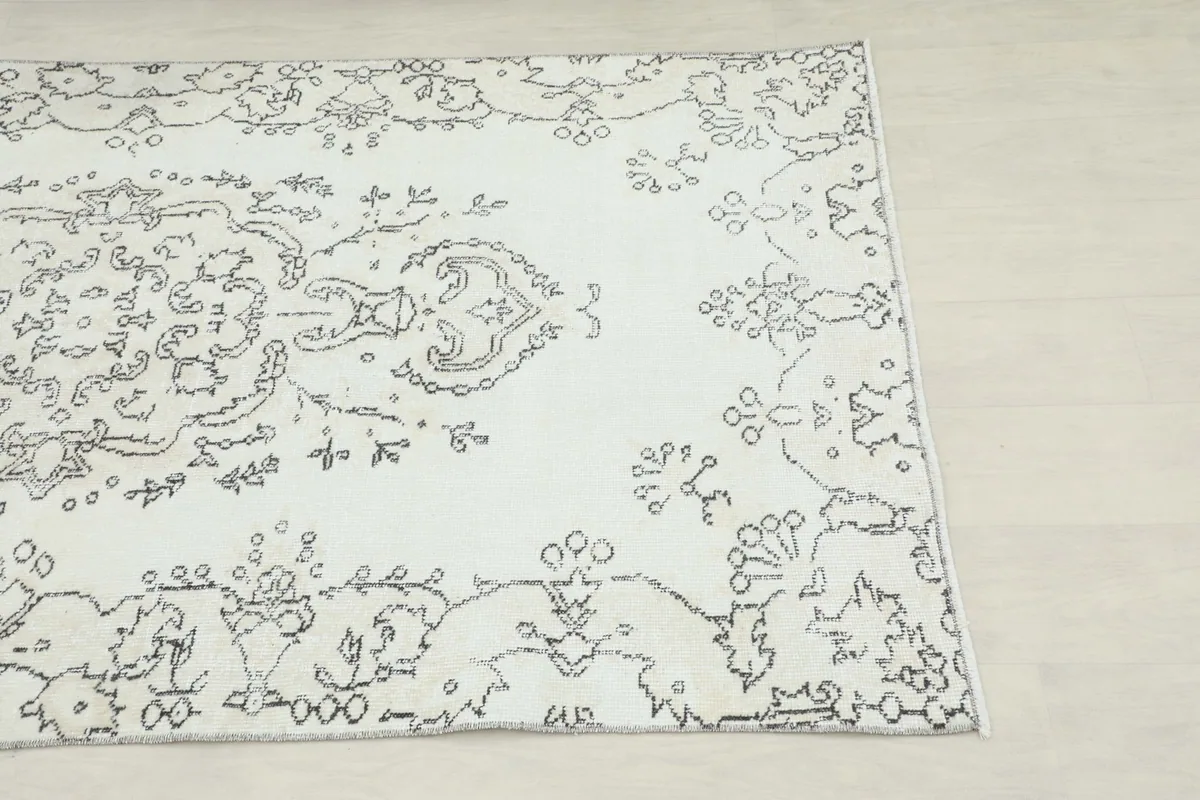 Close-up of the upper right corner of the rug, showing the faded charcoal patterns and ivory field.