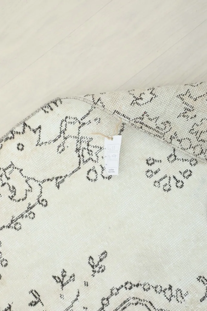 View of the rug's underside, revealing the tightly woven cotton foundation and visible knotting.