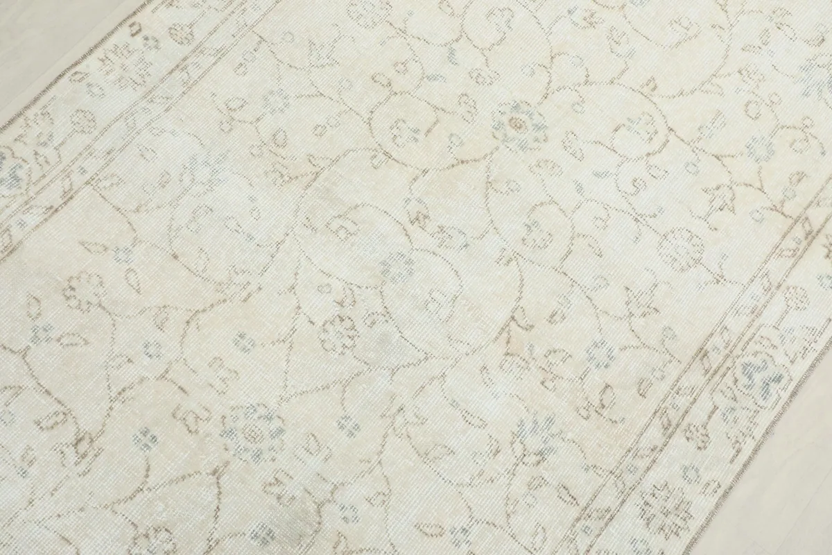 Detailed view of the rug's central field with intricate, faded floral and vine motifs