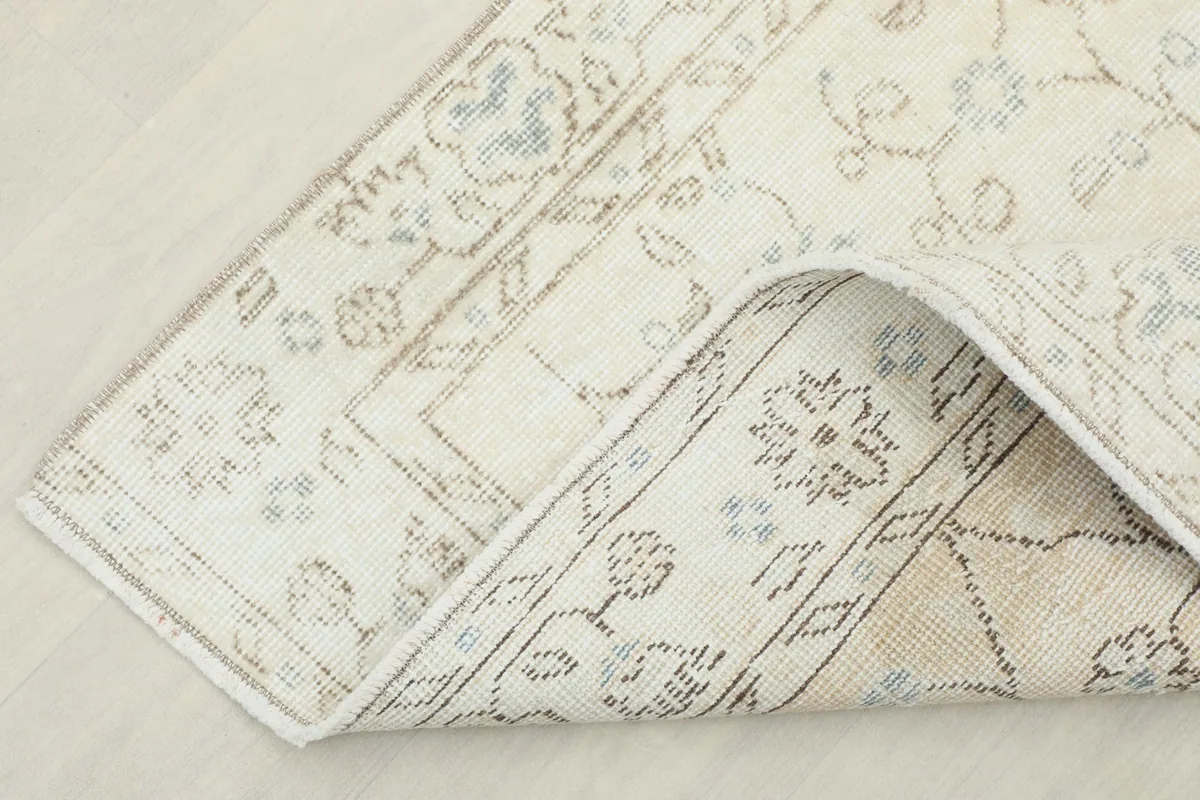 Corner of the rug folded back to show the cotton foundation and hand-knotted construction