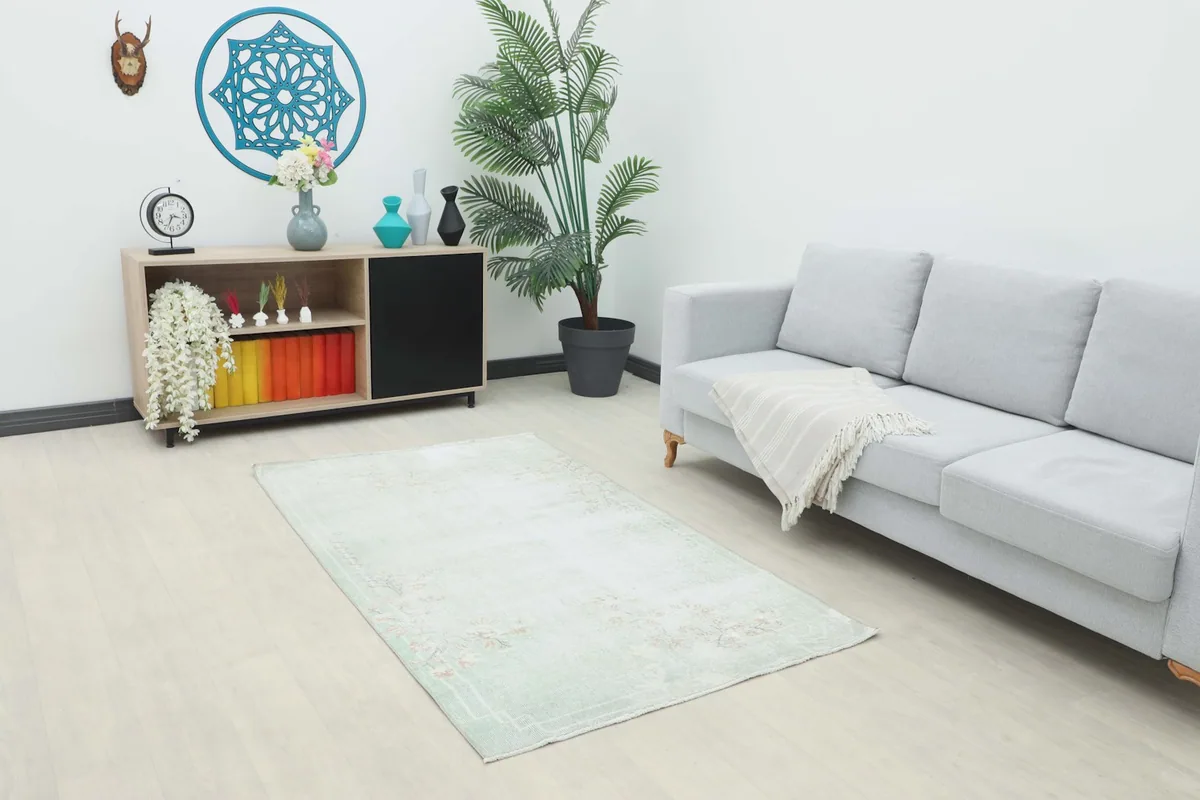The small green floral rug placed in a living room setting, complementing a gray sofa.