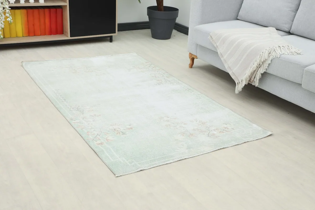 Angle view of the green and rose vintage rug in a living space, showing its size in context.