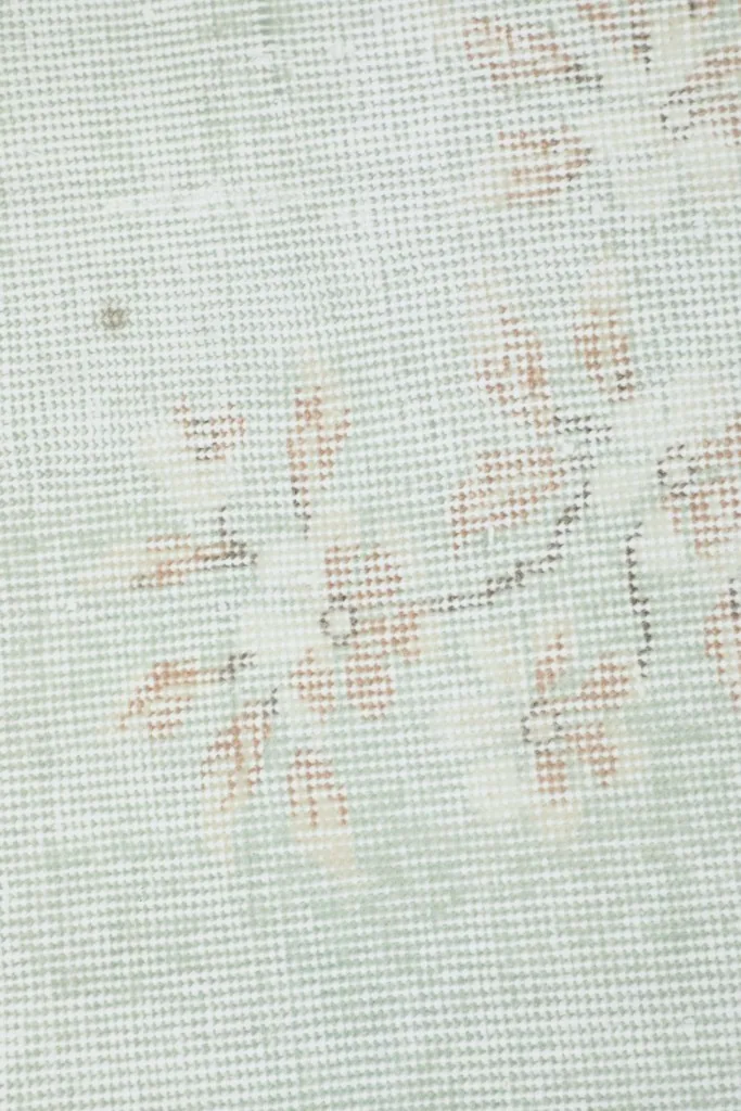 Close-up of the rug's low wool pile, showing the hand-knotted texture and color variations.