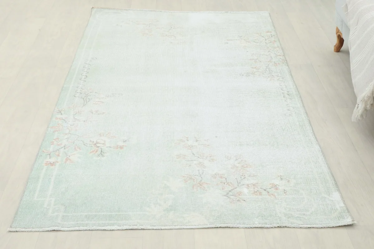 Overhead view of the vintage Anatolian rug, showcasing its soft green field and rose floral patterns.