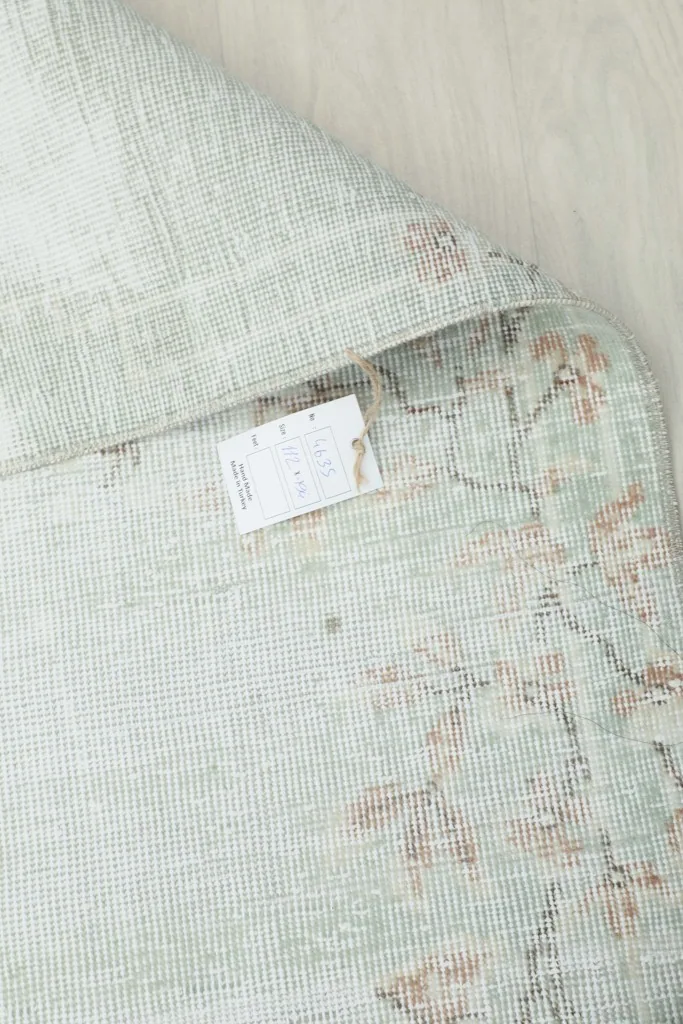 Close-up of the rug's back with a label, indicating its origin and material.