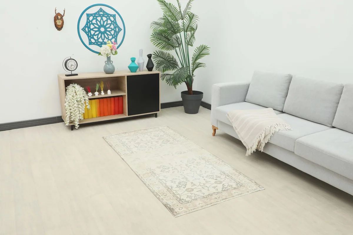 Ivory and tan vintage rug placed in a living room setting with a light gray sofa