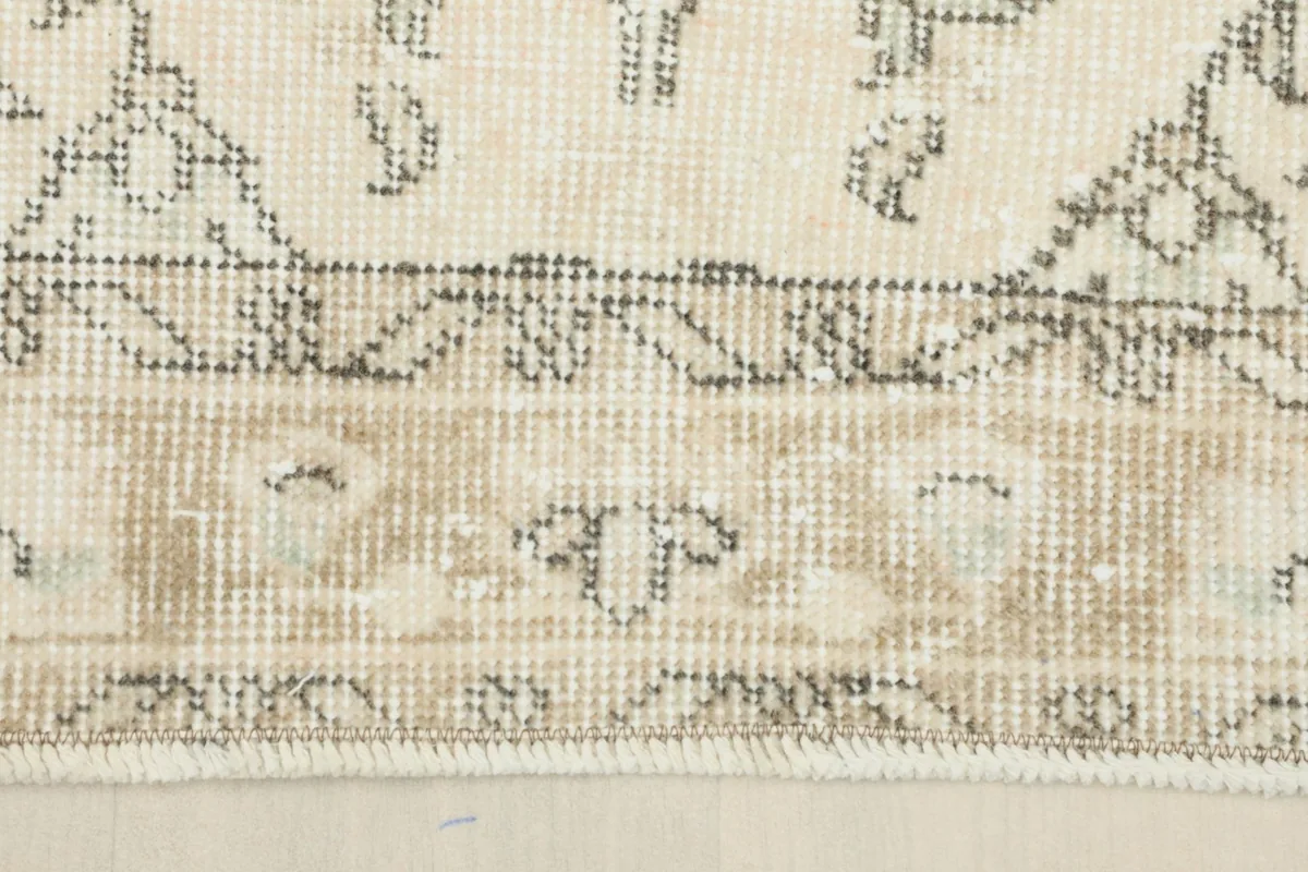 Detailed view of the rug's border, showing the tan tones and subtle patterns along the edge