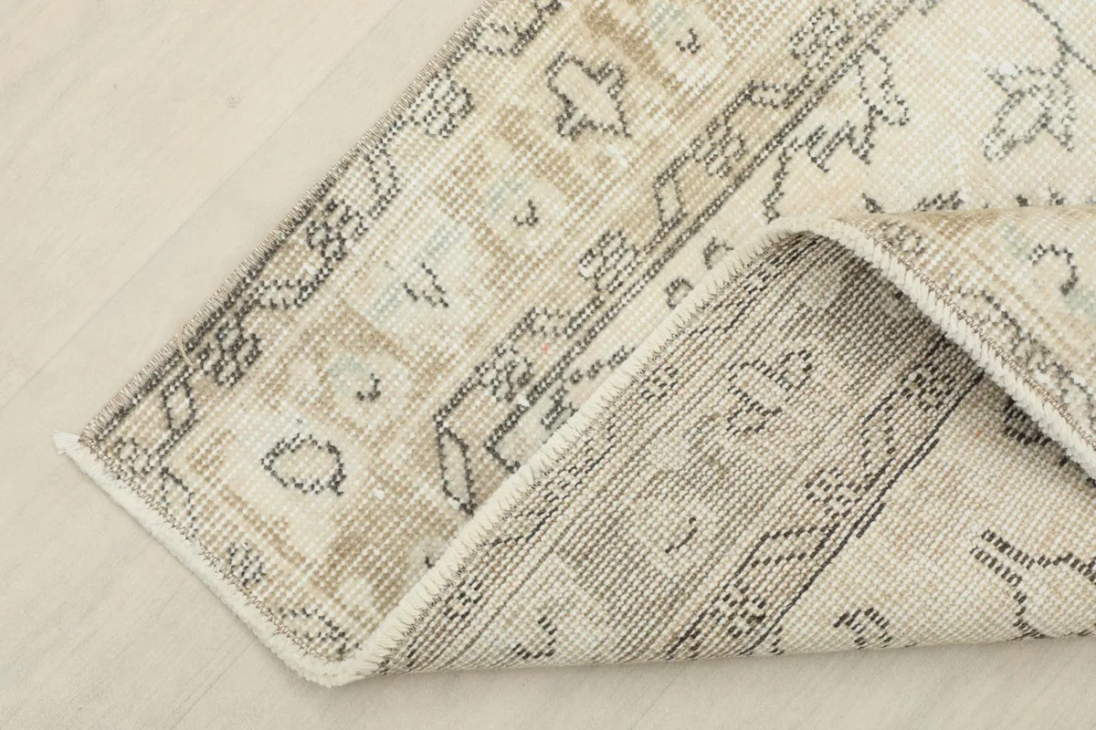 Corner of the rug folded back, displaying the wool pile and cotton foundation