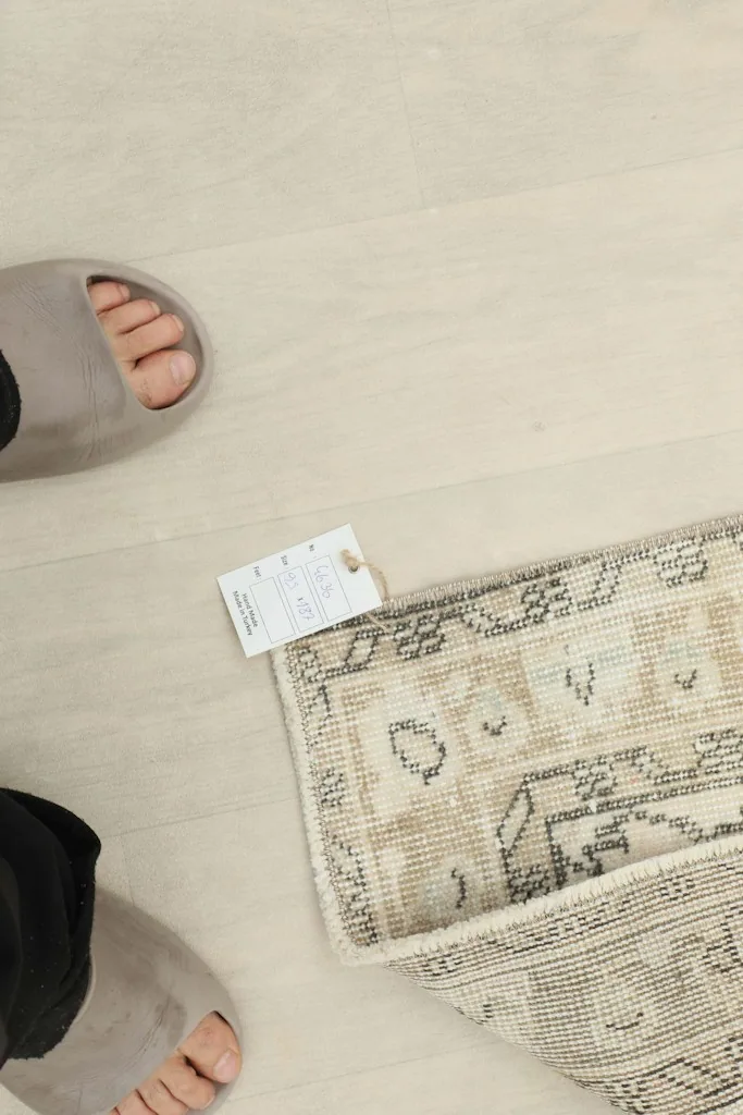 Overhead shot of the rug with a size tag next to a person's feet for scale