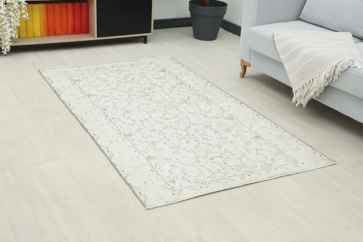 Angle view of the cream and gold floral rug in a room with a sofa