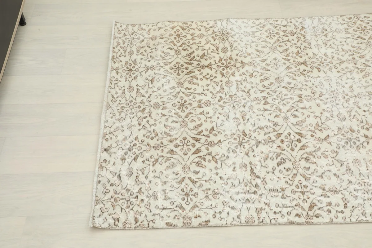 Corner view of the hand-knotted rug, showcasing the subtle beige motifs