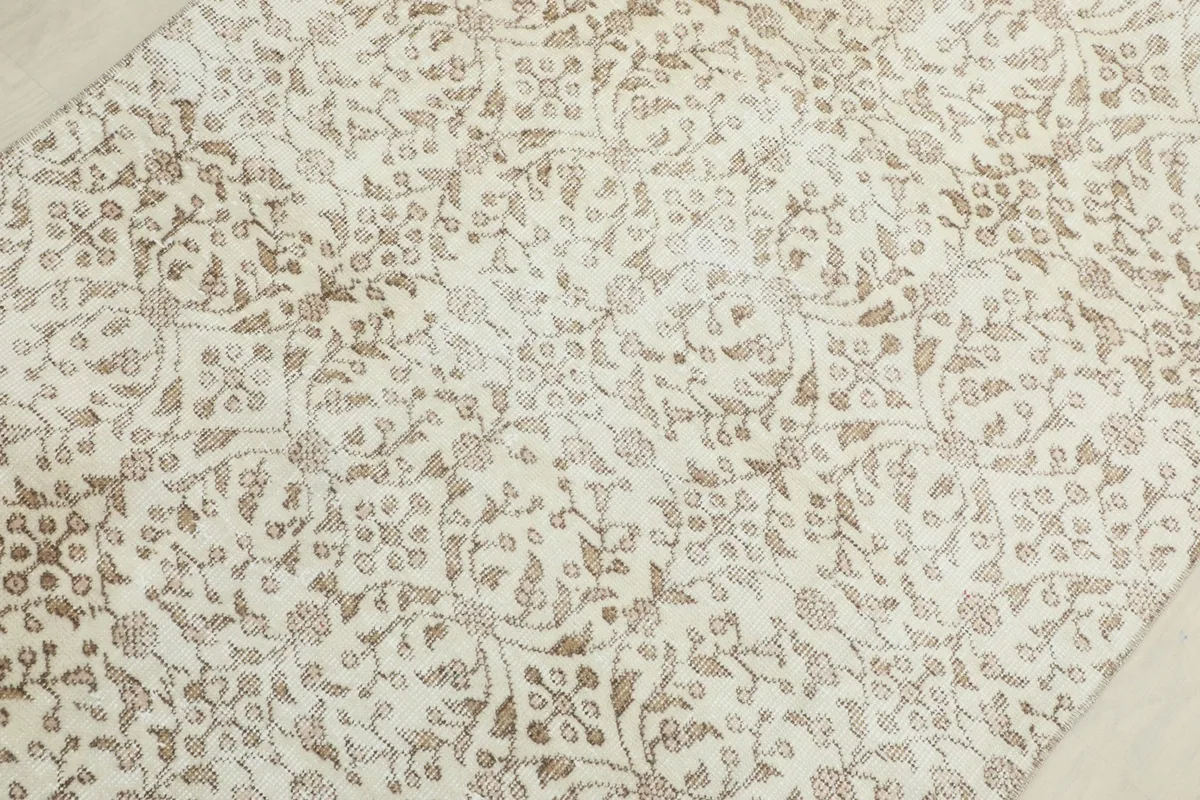 Close-up detail of the cream field and beige floral patterns on the rug