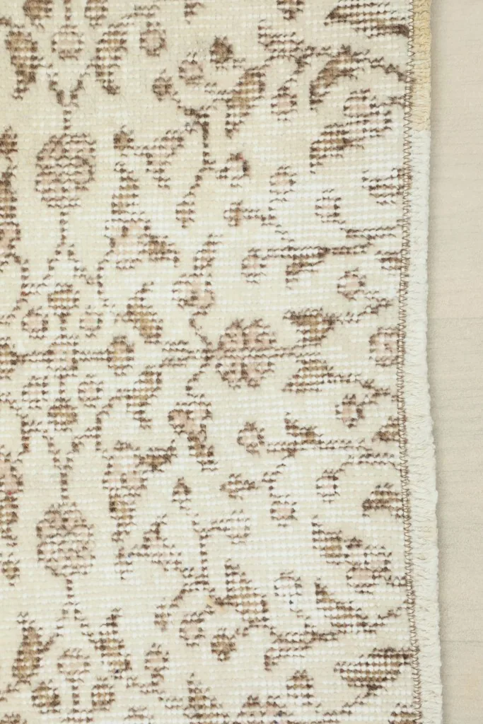 Detail showing the edge and a portion of the cream and beige floral pattern