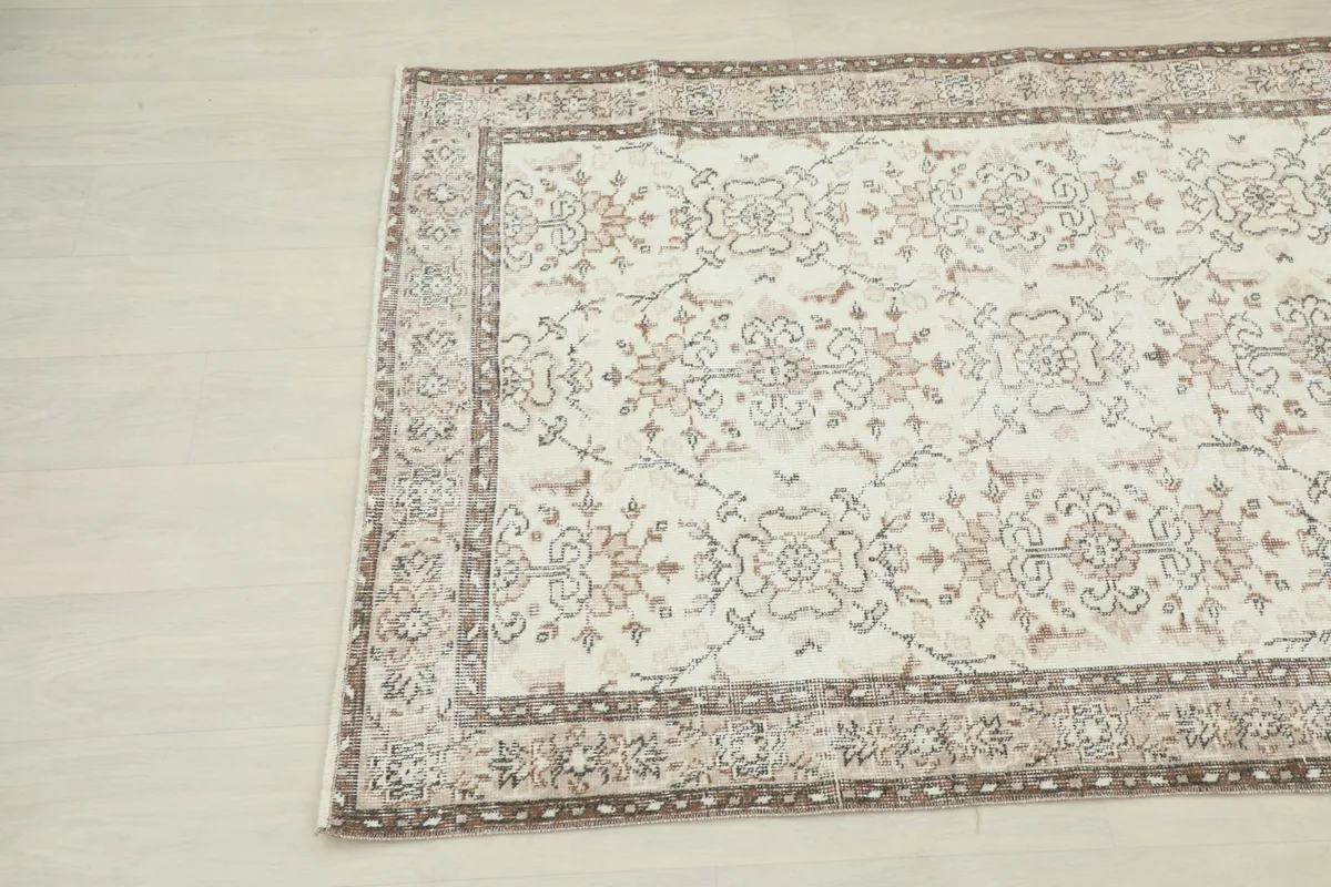 Corner view of the vintage ivory rug, showcasing the intricate details of the border design.