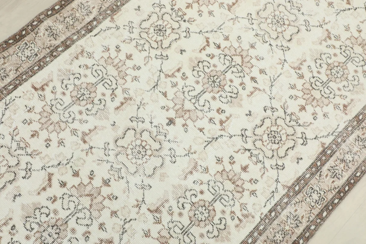 Overhead perspective of the ivory rug's center, revealing the repeating floral and geometric patterns.