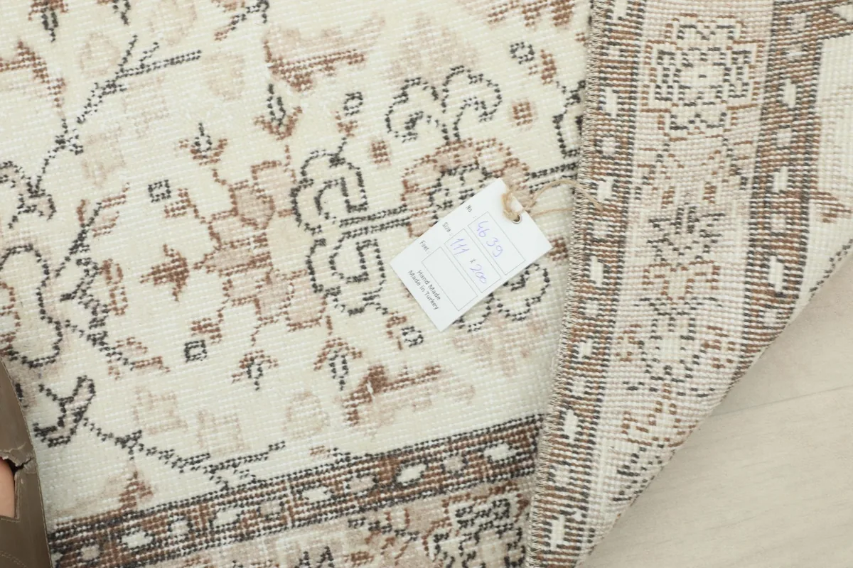 A close-up of the rug's texture and a care tag, with a corner folded to show the backing.