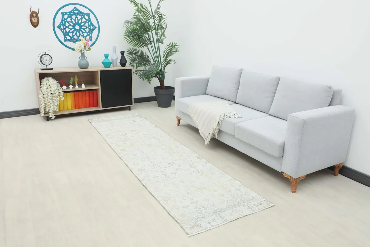 Ivory floral runner rug laid out in a modern living space next to a light gray sofa
