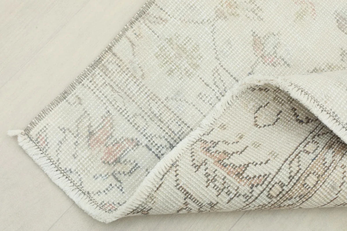 Corner of the rug folded to reveal the cotton foundation and reverse side of the hand-knotted construction