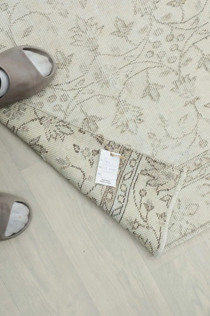 View of the rug with a tag attached, showing the back and the hand-knotted details near slippers