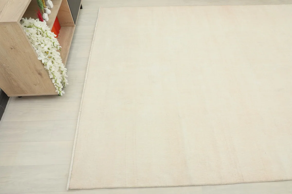 Overhead angle shot of the cream and rose rug, showing its placement next to a light wood cabinet