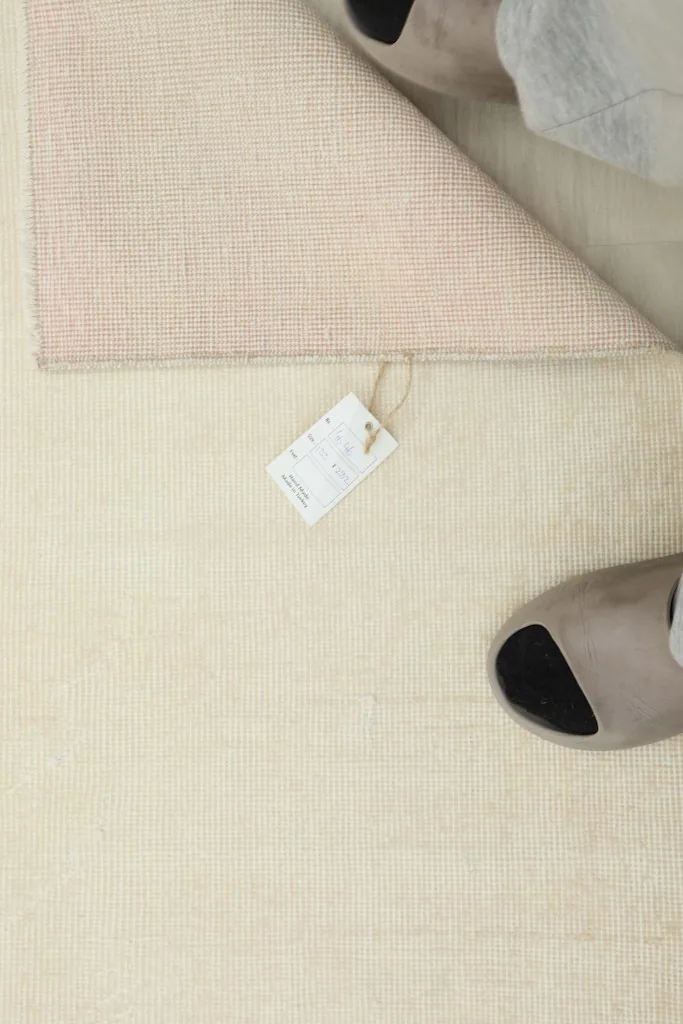 Overhead detail showing the rug's label and the texture of the back, next to a pair of slippers