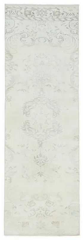 Full top view of an ivory runner rug with faded gray and tan floral motifs
