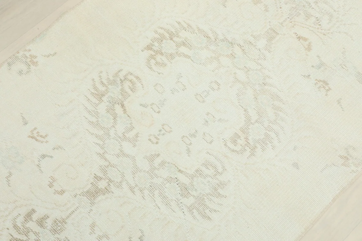 Detailed view of the rug's central medallion-like motif in muted tones