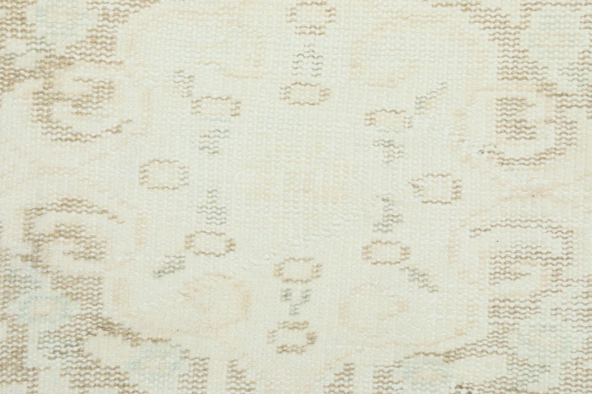 Close-up of the intricate, faded gray and tan patterns on the rug's surface