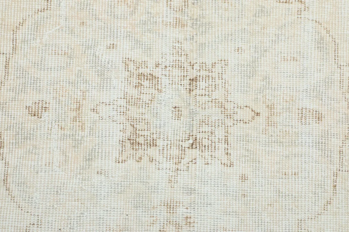 Macro detail of the faded brown and beige tones within the rug's pattern
