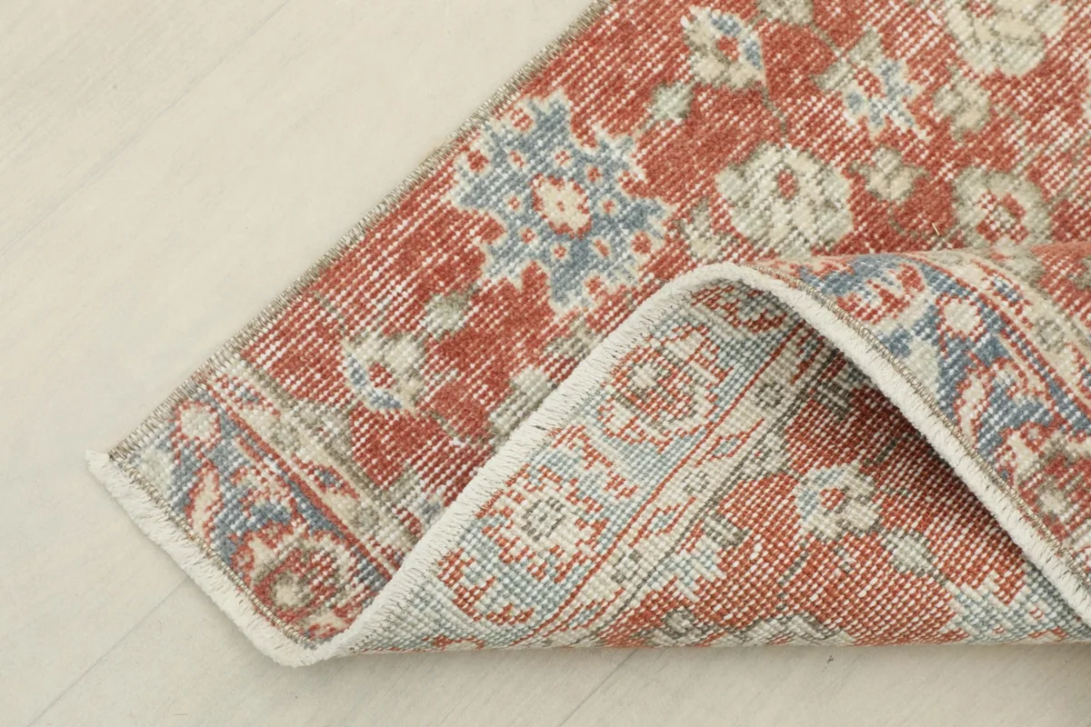 Corner of the rug folded to reveal the cotton foundation and hand-knotted construction