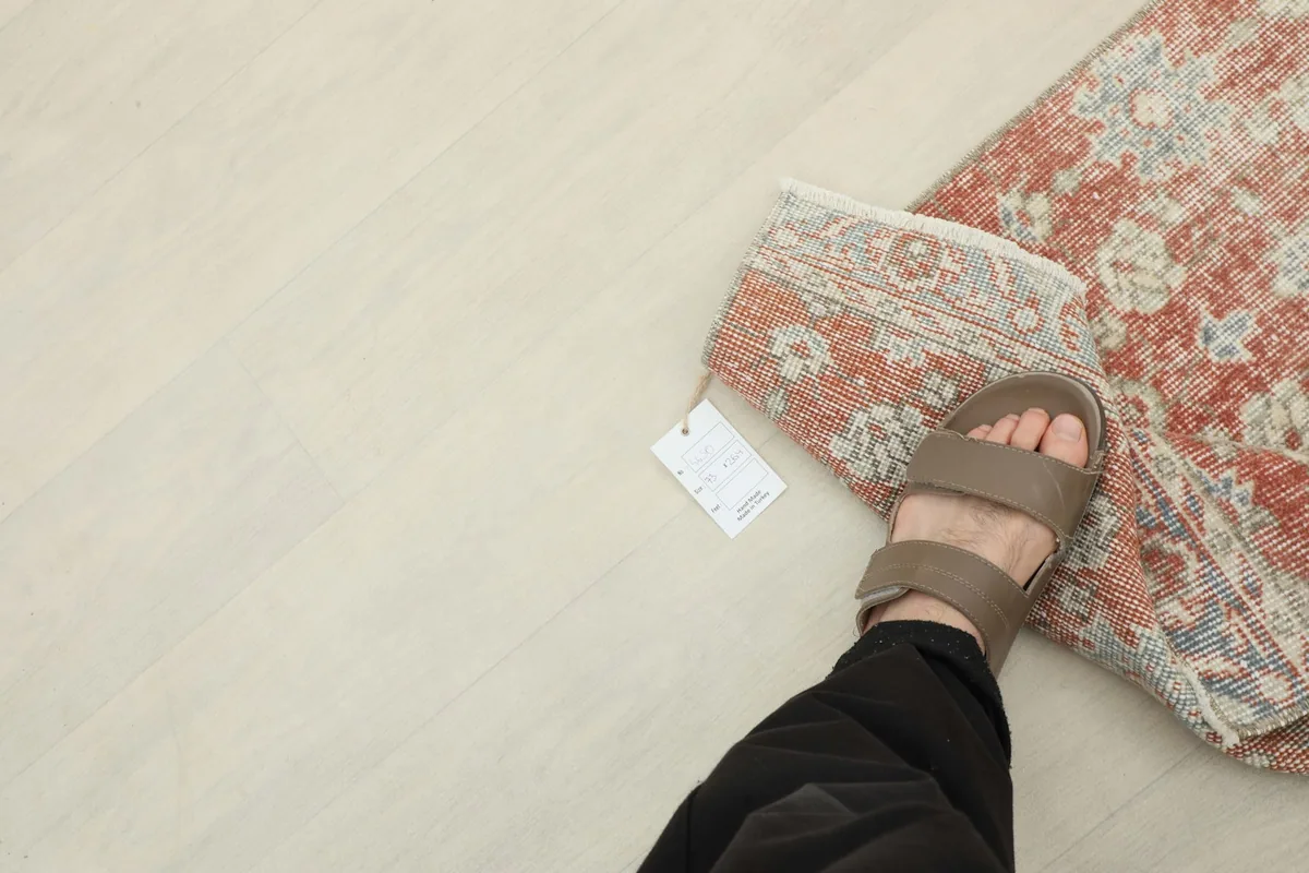 Overhead view with a foot for scale, showing the rug's size and tag