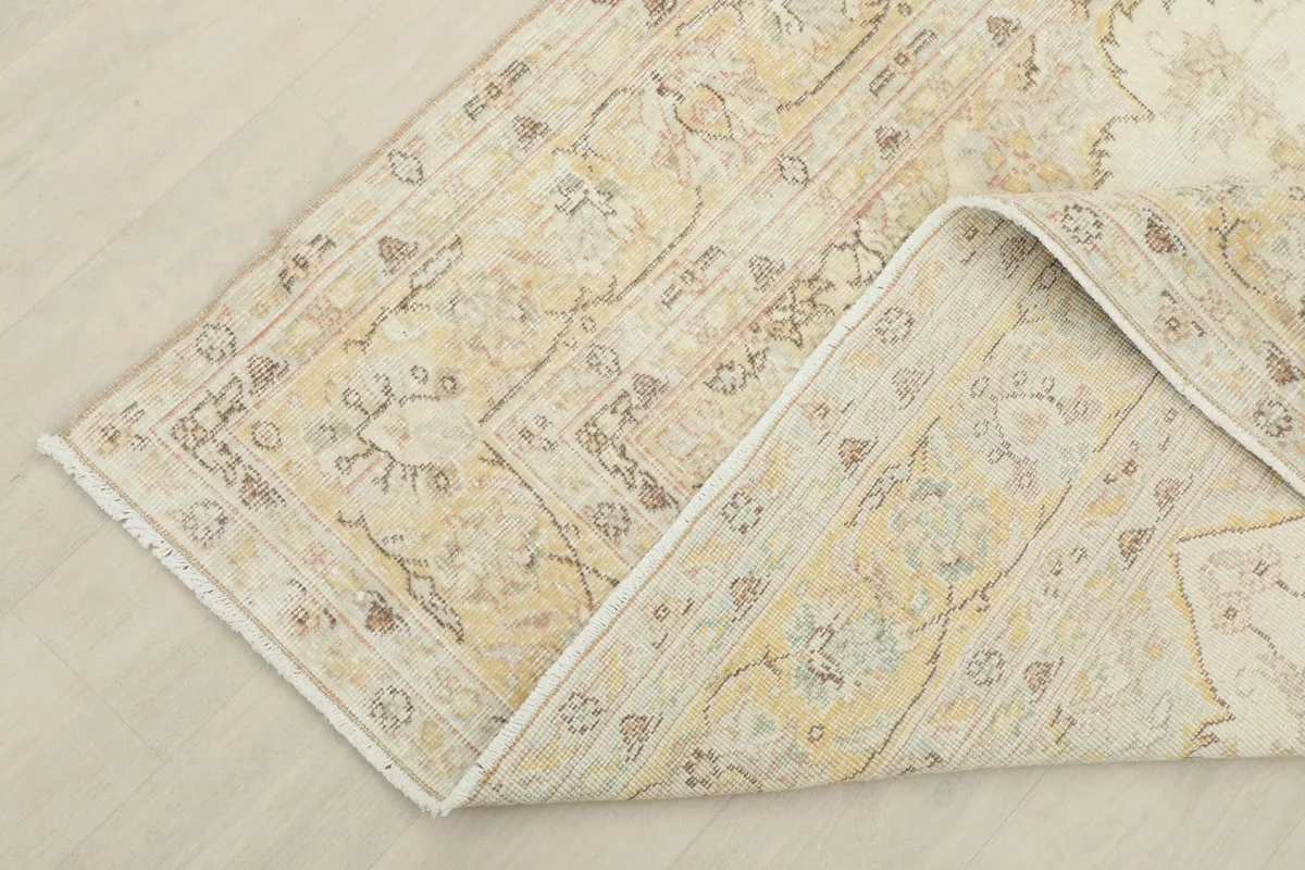 Corner of the vintage rug folded back, revealing the cotton foundation and the quality of the hand-knotting.