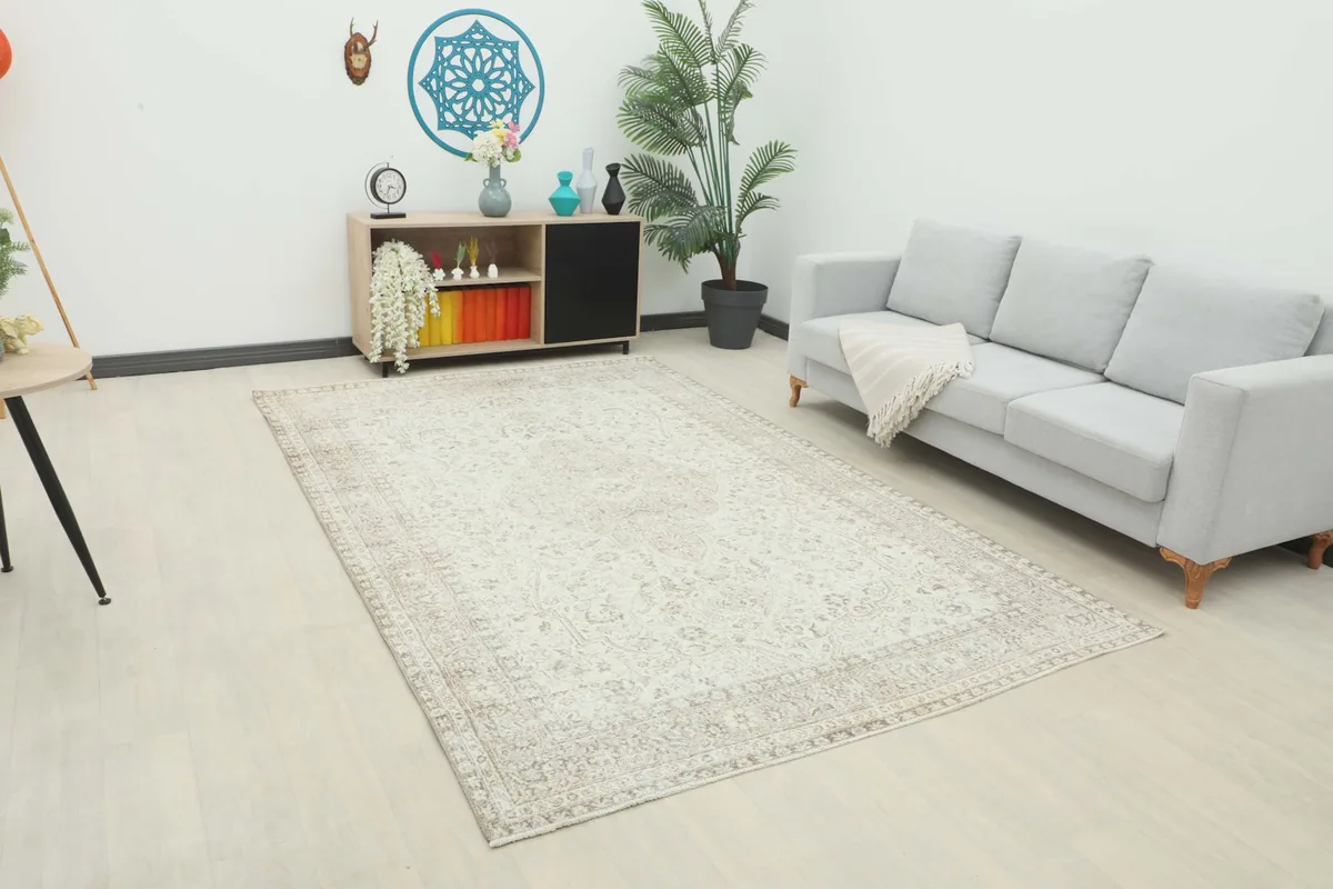 Full view of the large ivory and beige vintage rug in a living room setting with a sofa and decor.