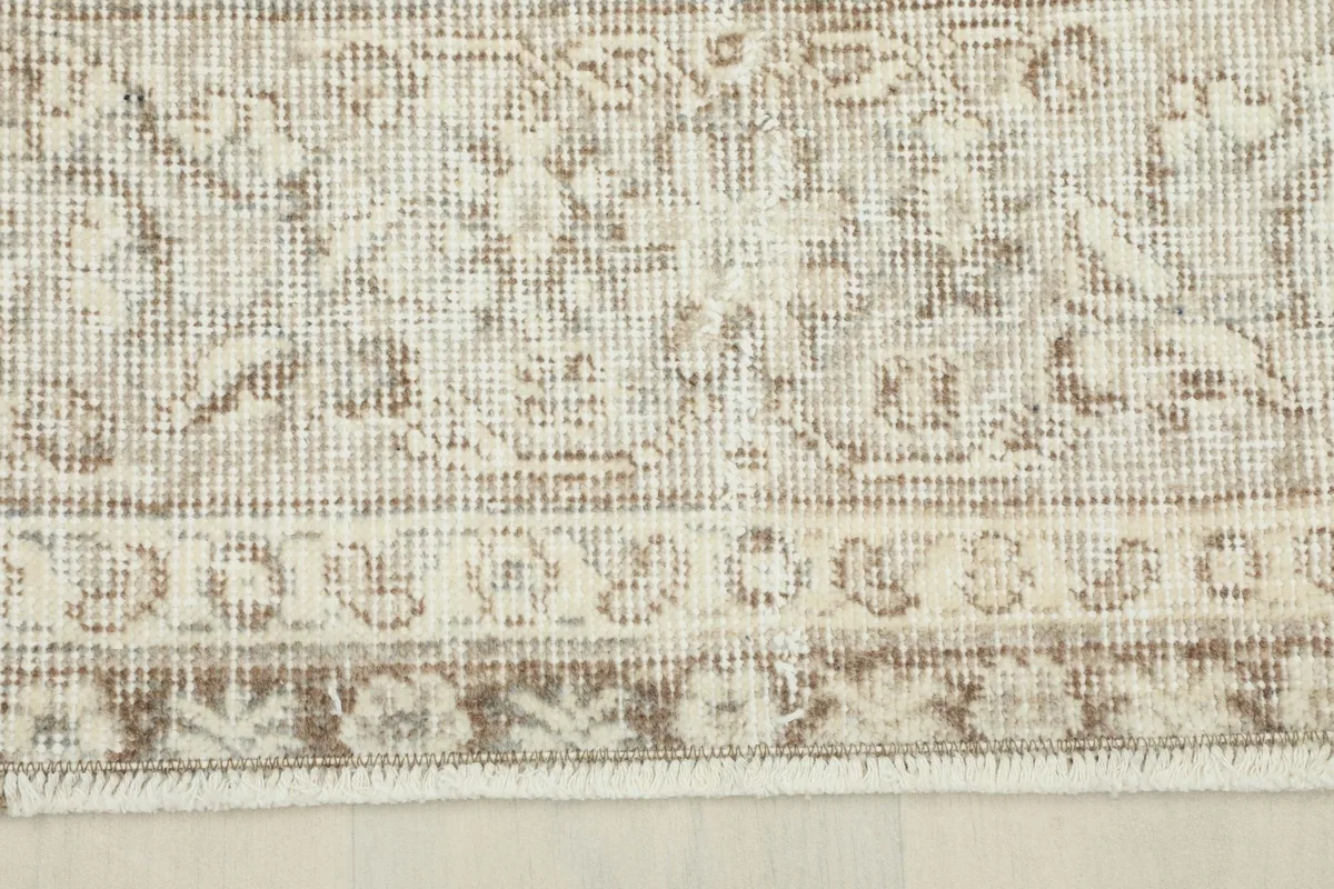 Close-up of the rug's border design, featuring intricate patterns and the low pile.