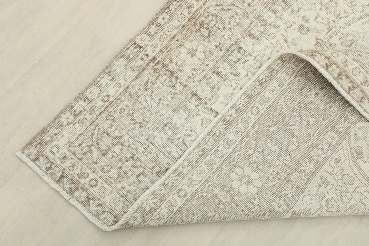 View of the rug's underside and folded edge, revealing the cotton foundation and knotting.