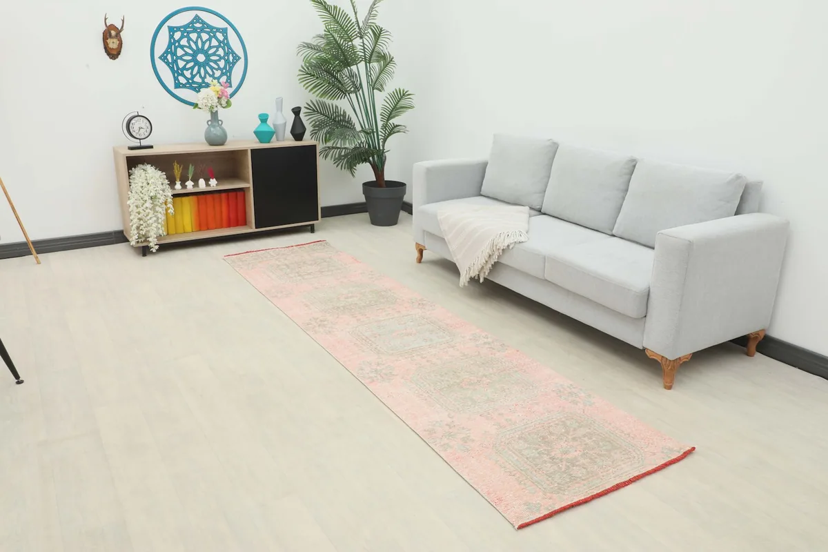 Long shot of the rose and green runner rug placed in a modern living space with a gray sofa.