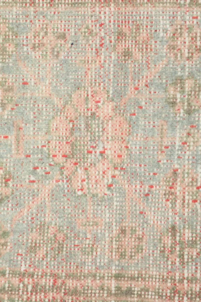 Extreme close-up showing the low pile and intricate hand-knotted texture of the rug's surface.