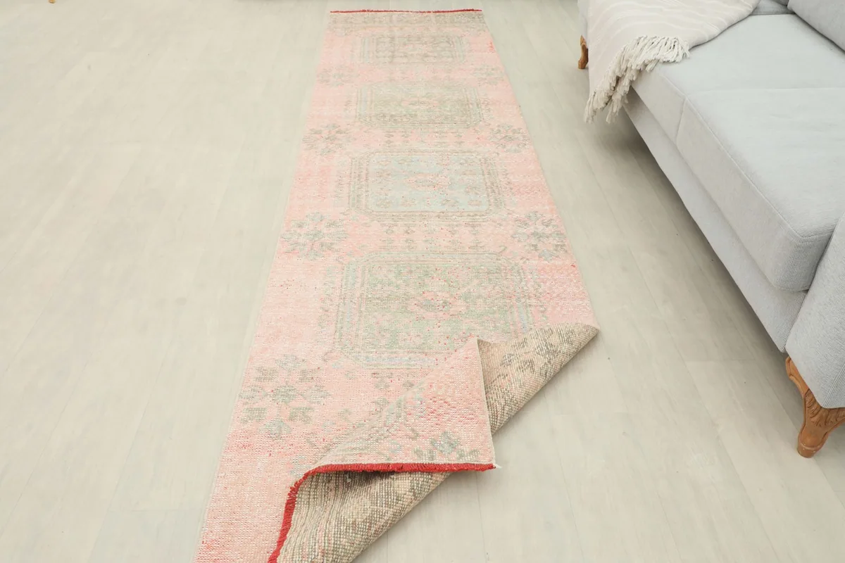 The runner rug partially folded back, showing the underside and its placement in a room setting.
