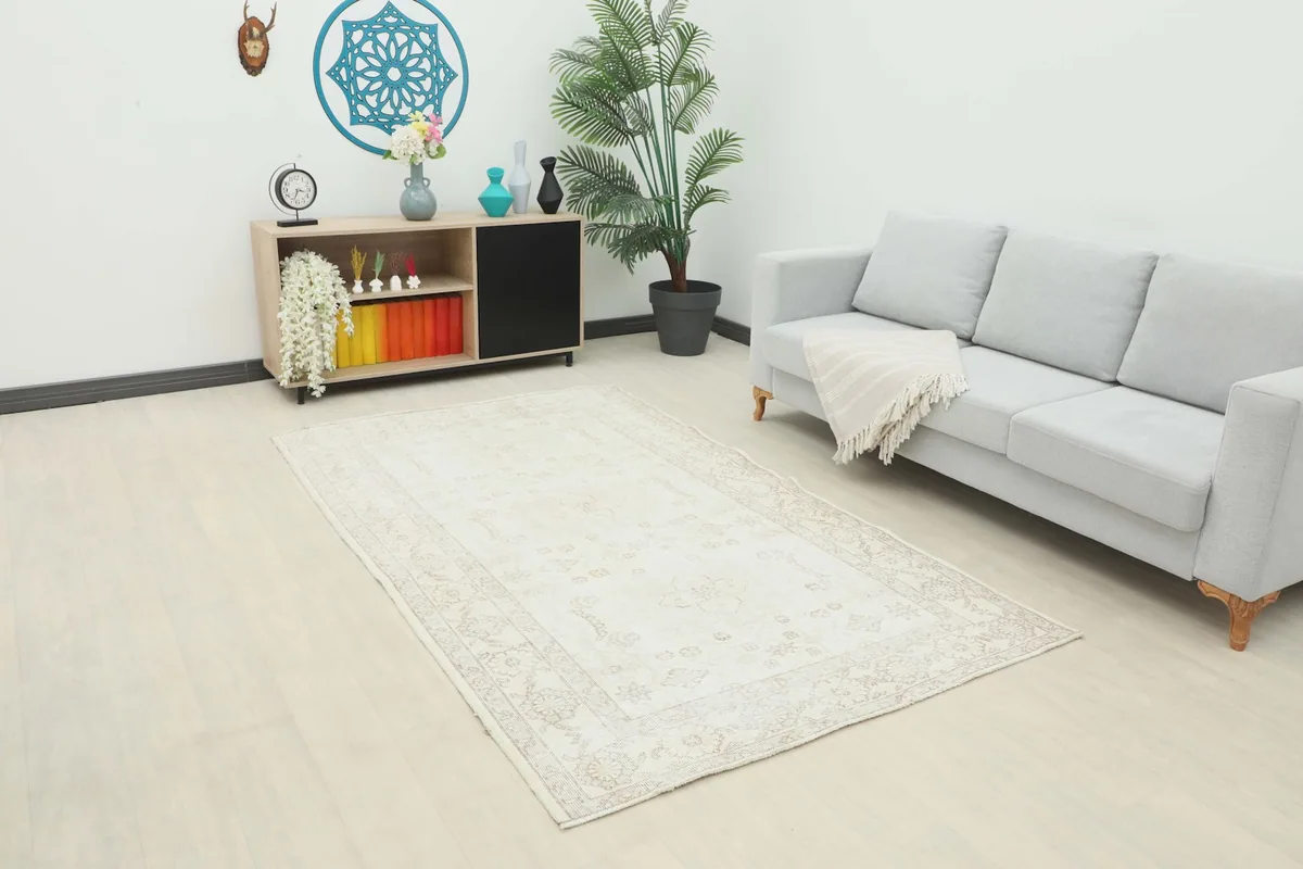 Vintage Anatolian rug displayed in a room setting with a light gray sofa and wooden cabinet.