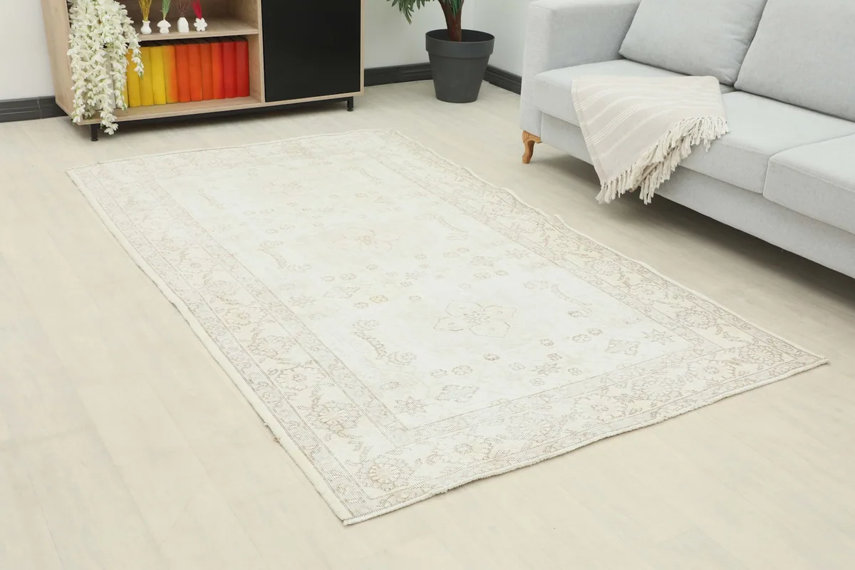 Angled view of the ivory and beige rug in a room, showing its placement relative to furniture.