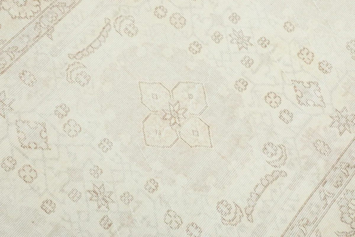 Detailed view of the central geometric motifs in beige against the ivory field.