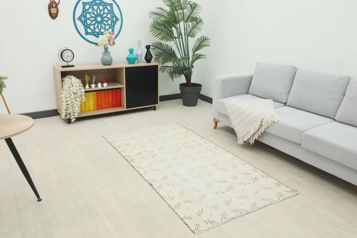 The cream geometric rug placed in a modern living space with a gray sofa and wooden cabinet, showing its scale.