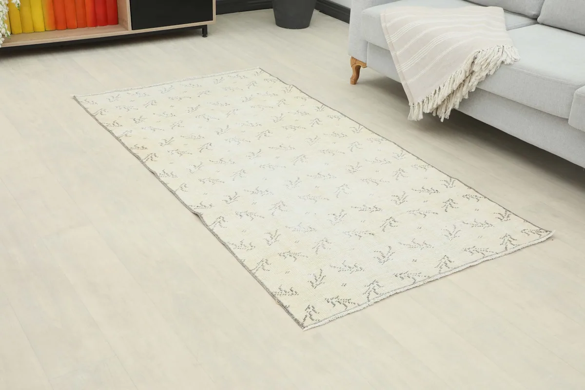 Angled view of the cream and charcoal geometric rug in a living room setting, highlighting its placement.