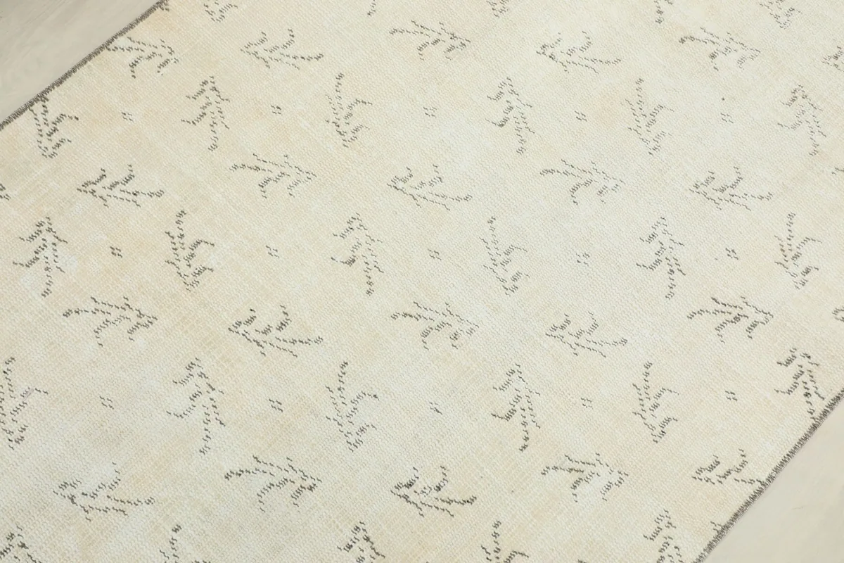 Detailed view of the hand-knotted charcoal geometric patterns on the cream wool pile of the vintage rug.